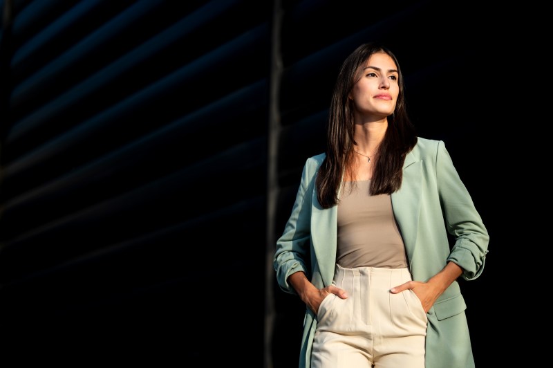 Young adult businesswoman standing outdoor against black background on a sunny day